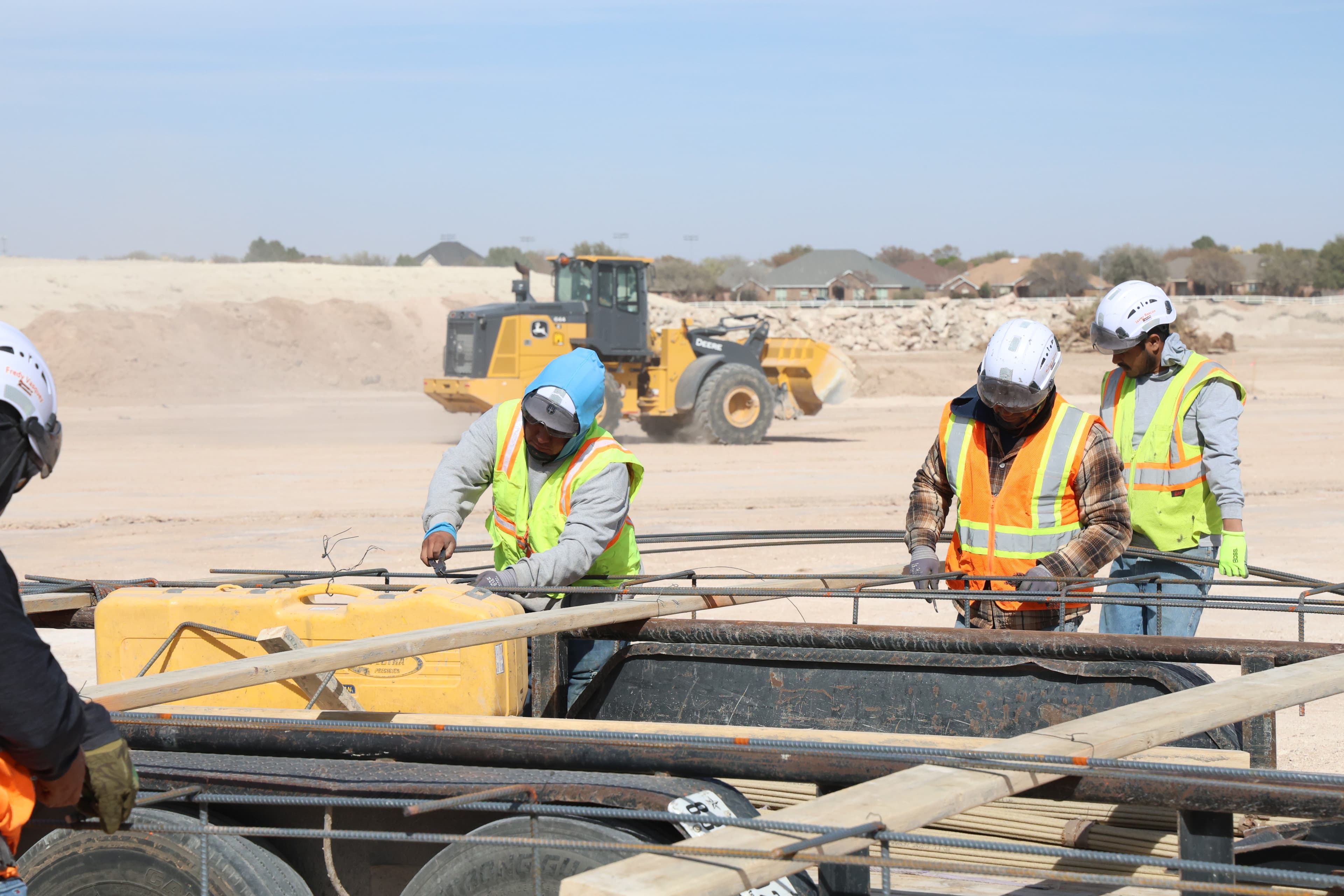 Packed Industries crew handling rebar with a wheel loader operating in the background